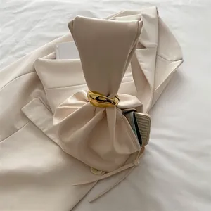 Sac seau plissé beige minimaliste avec anneau doré montrant ses accessoires essentiels