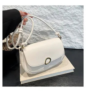 Detail of creamy white saddle bag showing golden ring buckle and knotted strap on books