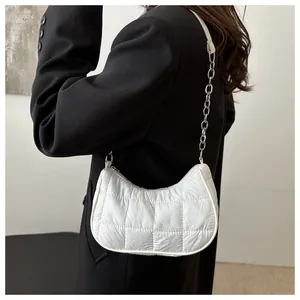 Detail of white quilted nylon hobo bag with silver chain strap worn by a model
