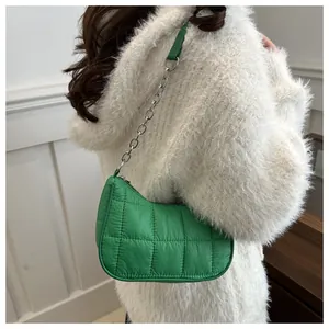 Detail of green quilted nylon shoulder bag with silver chain strap on a white sweater