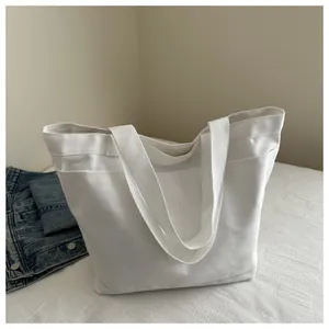 Top view of white canvas tote bag with wide straps and exterior pocket detail