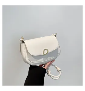 Close-up of a white saddle bag featuring a gold metal buckle and knotted strap detail