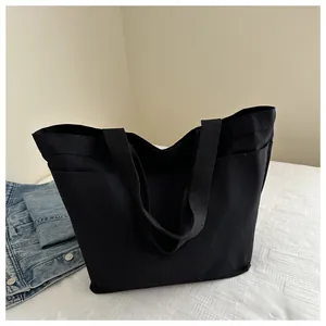 Detail of a large black canvas tote bag with side pockets and durable woven handles