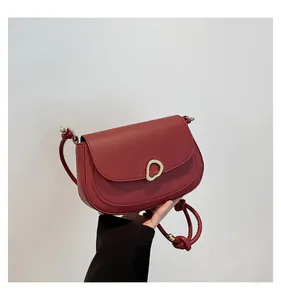 Close-up of a burgundy saddle bag featuring a streamlined gold metal buckle and leather knot