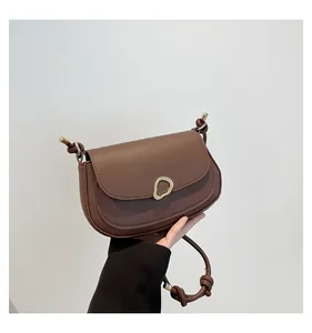 Detail of vintage coffee saddle bag showing golden hardware and matte PU leather texture