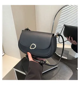 Detail of a black minimalist saddle bag with unique gold ring buckle and leather cord strap