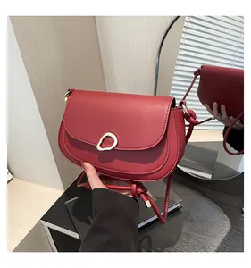 Detail of red saddle bag featuring gold teardrop clasp and knot shoulder strap