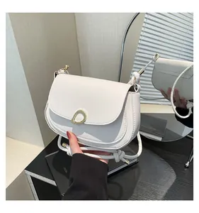 Detail of white saddle bag with golden ring buckle and knotted strap shown in a mirror