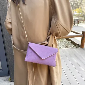 Minimalist purple matte envelope chain bag with gold metal strap on khaki trench coat