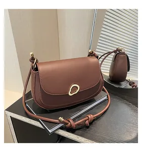 Detail of dark brown saddle bag with gold buckle and knotted strap on mirror