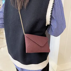 Minimalist burgundy suede envelope crossbody bag with a delicate gold chain strap for women