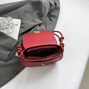 Minimalist red saddle bag with matte leather finish and golden metal twist lock closure