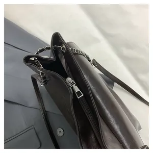 Detail view of the metal zipper and interior compartments of this dark brown tote bag