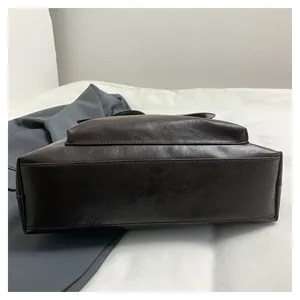 Detailed view of the wide base and fine stitching on a dark brown vintage tote bag