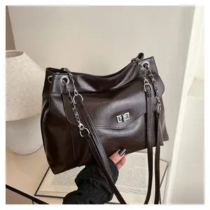 Detail of dark brown faux leather bag with silver square twist lock and metal chain strap