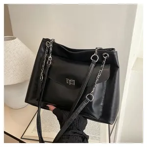 Detail view of a black leather tote bag with turn-lock metal clasp and chain shoulder strap