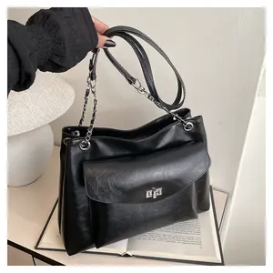 Detail showing the large black leather tote bag with silver turn-lock and chain strap