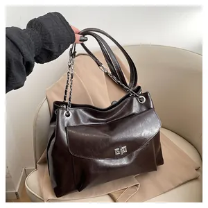 Detail of dark brown faux leather tote bag with silver twist lock and chain strap
