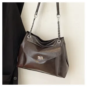 Detail of dark coffee leather tote bag with silver metal twist lock and chain strap