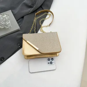 Glossy gold evening chain bag with sequins and leather, shown next to phone for size scale