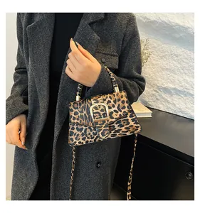 Detail of leopard print handbag with gold buckle shown on a stylish grey coat