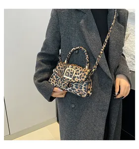 Detail of leopard print handbag with gold metal buckle shown on a model