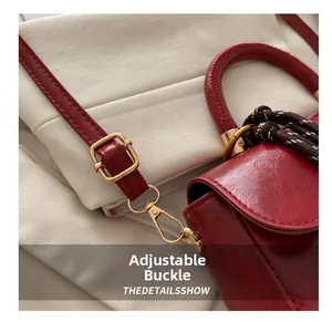 Dettaglio borsa rossa in pelle PU con fibbia dorata regolabile e decorazione intrecciata