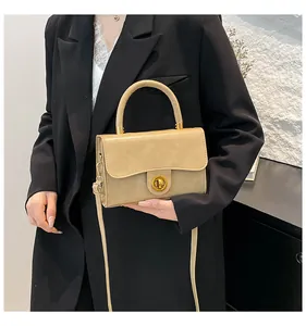 Détail d'un sac à main en cuir kaki avec fermoir doré et bandoulière sur blazer noir