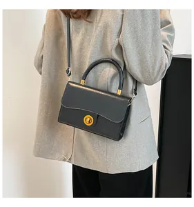 Détail d'un sac à bandoulière en cuir noir avec ferrures dorées et poignée chic