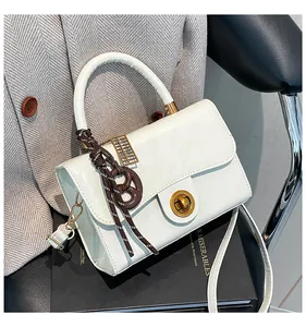 Détail du sac à main crème avec fermoir doré et charme d'abaque sur des livres