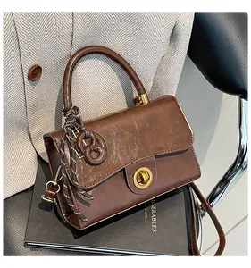 Détail du sac à main en cuir synthétique marron avec fermoir doré sur livres