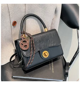 Détail du sac à main en cuir noir avec fermoir doré et accessoire décoratif