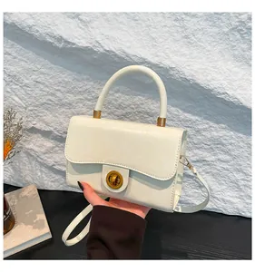Détail d'un sac à main en cuir crème montrant le fermoir doré et la texture fine