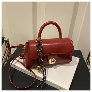 Dettaglio della borsa in pelle PU rossa con chiusura dorata e nappina a campanello