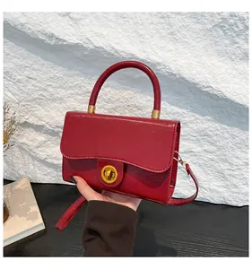 Détail du sac à main en cuir verni bordeaux avec fermoir doré et rabat festonné