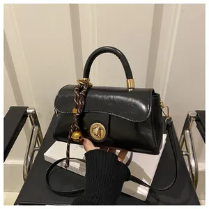 Dettaglio della borsa nera lucida con chiusura a scatto dorata e cordoncino decorativo