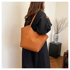 Borsa tote in pelle marrone indossata con cappotto nero in un ambiente minimalista