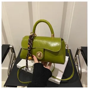 Dettaglio borsa a mano verde lucida con chiusura dorata e decorazione foulard di seta