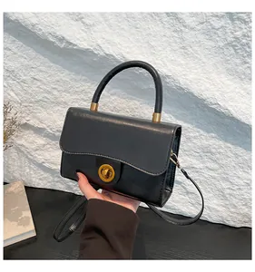 Détail du sac noir avec rabat ondulé et fermoir rotatif métallique doré chic