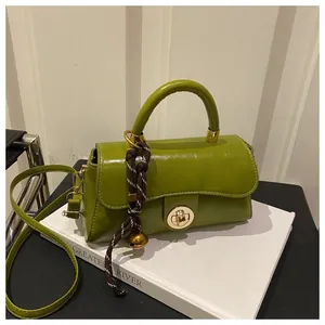 Dettaglio borsa a tracolla verde in ecopelle con fibbia dorata e ciondolo