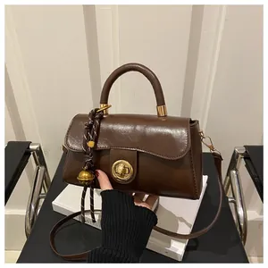 Dettaglio borsa tote in pelle marrone scuro con chiusura girevole dorata e ciondolo