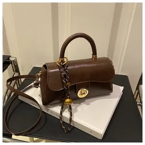 Dettaglio macro della borsa vintage marrone scuro con chiusura dorata e ciondolo intrecciato
