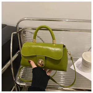 Dettaglio borsa in pelle verniciata verde con chiusura a scatto dorata e metallo