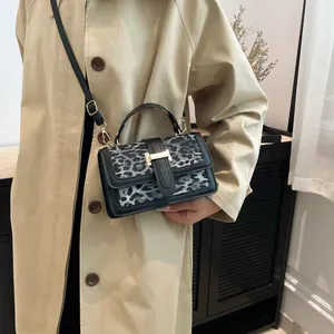 Fashionable leopard print handbag with gold H buckle and adjustable strap on a model