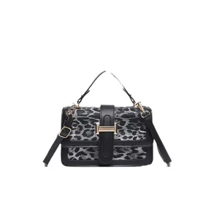 Leopard print crossbody bag with gold hardware and top handle on a white background
