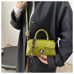Dettaglio borsa in pelle verde avocado con chiusura a scatto dorata e cinturino intrecciato