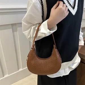 Brown woven crescent shoulder bag with minimalist semi-circle texture and zipper closure