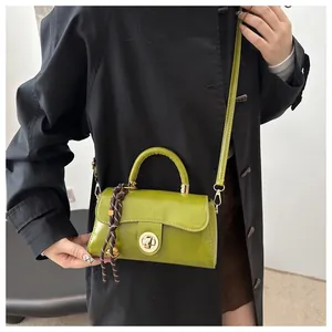 Dettaglio di una mini borsa a tracolla retrò verde oliva con chiusura in metallo e charm