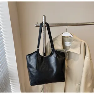 Detail of glossy black oil wax leather tote bag with adjustable shoulder straps