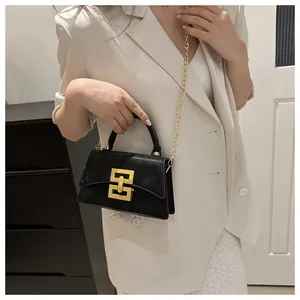 Detail of elegant black flap handbag with gold geometric clasp and chain strap
